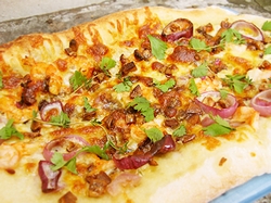 「異国風味なピザのトッピング」の一例として挙がった赤タマネギやエビやスカンピなどのトッピングを盛り付けたピザ(2008年)の画像