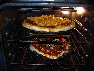フライドポテトをトッピングしたピザと、ドライトマト、ブラックオリーブ、およびペパローニをトッピングしたピザ。「完全菜食主義ピザ」。(2012年)